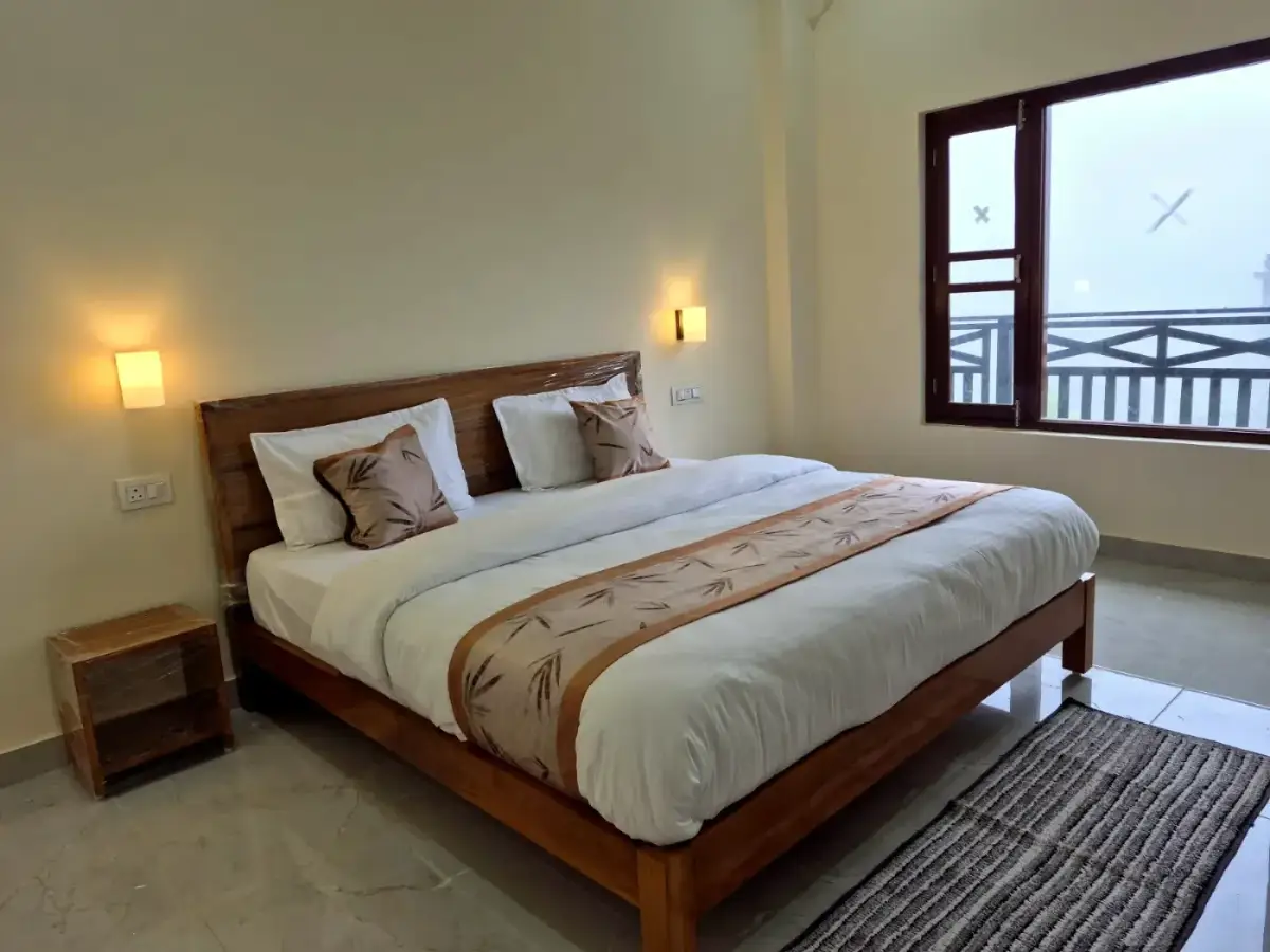 King bed with wooden frame, warm sconces and a misty valley view